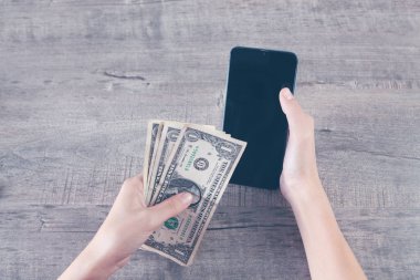 Elinde telefon ve banknotlar tutan genç bir kız.