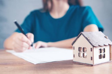 Kadın evin önündeki hesap makinesine güveniyor.