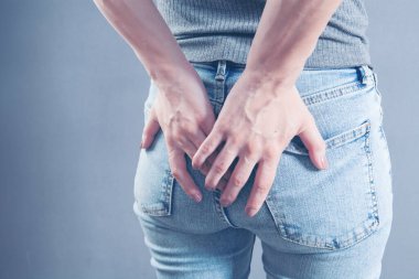 woman holding ass. hemorrhoids concept