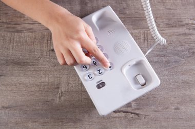 Bir kadın ev telefonundaki bir numarayı çevirir.