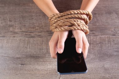 Bir iple bağlanmış kadın elleri telefonu tut.