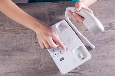 Bir kadın ev telefonundaki bir numarayı çevirir.