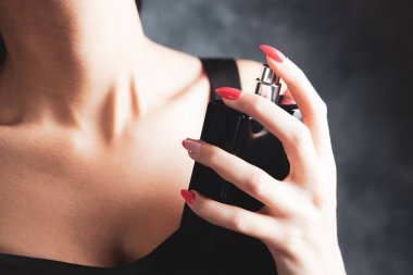 Kadın boynuna parfüm serpiyor.