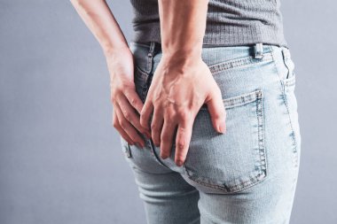 woman holding ass. hemorrhoids concept