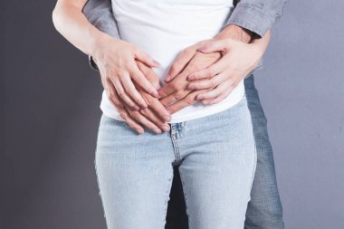 Bir erkek bir kadına arkadan sarılır.