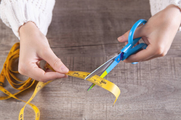 женщина режет измерительную ленту ножницами