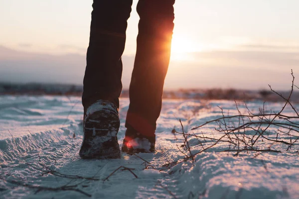 Bir adam gün batımında karda yürür..