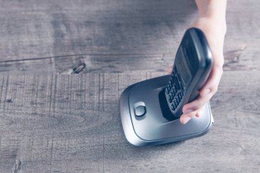 Bir kadın ev telefonundaki bir numarayı çevirir.