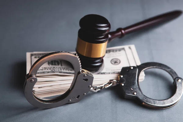 テーブルの上の判事のハンマーと手錠とお金 — ストック写真