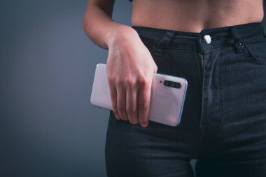 Kot pantolonlu kadın telefonla poz veriyor.