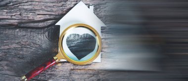 Büyüteç ve masa üzerinde kalp şeklinde bir ev