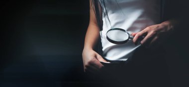 Bir kadın kasıklarına büyüteçle bakar.