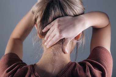 Boynuna masaj yapan bir kadının eline yakın çekim. Kızın boynu ağrıyor.