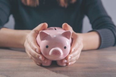 Steteskoplu doktor gri arka planda kumbarasını tutuyor.