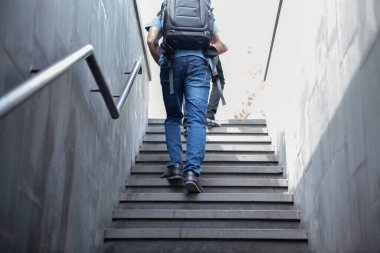 Sırt çantalı bir turist merdivenlerden çıkıyor.