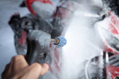 Adam çamaşır makinesinde motosiklet temizliyor.