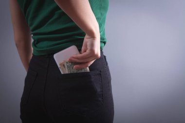 young woman puts phone in back pocket 