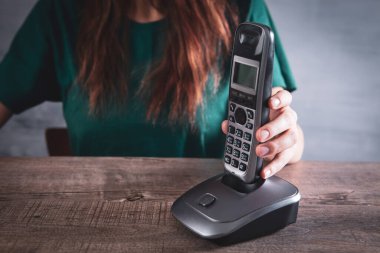 Bir kadın ev telefonundaki bir numarayı çevirir.