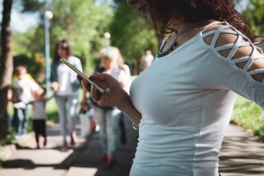 Genç bir kız elinde telefonla dikiliyor.