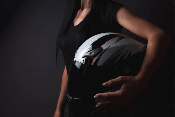 woman stands holding helmet from motorcycle