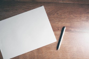 Masanın üzerinde bir kağıt ve bir kalem var.