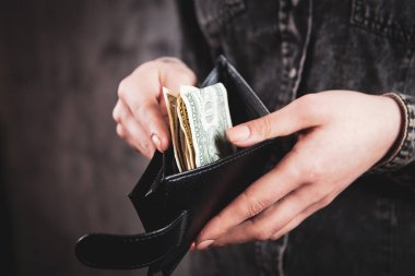 Kız cüzdanı elinde tutuyor ve parayı alıyor.