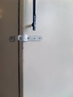 Kırık demir menteşeli eski bir buzdolabı. Aşırı yiyecek tüketimi bağlamında insan iradesinin zayıflığıyla ilgili bir hikaye. Obezite, Covid-19 tecrit sırasında uzaktan çalışmanın dezavantajıdır..