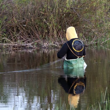 Kyiv, Ukrayna-11 Nisan 2022: Efsanevi CIA ajanı Hellboy nehirde görüldü, bir ağla balık tutuyordu. Sırtında Hellboy Survival yazıyordu. Yukarıdan Rusya 'nın Ukrayna' yı işgalinin sembolü V sembolü olan kırık bir dal görebilirsiniz..