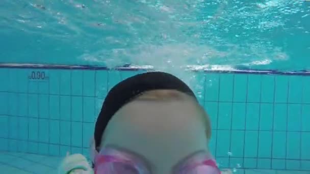Cute little girl goes in for sports in the outdoor pool and swims underwater — Stock Video