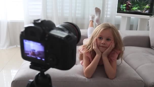 Graciosa niña sonriendo mirando a la cámara en casa, haciendo videollamada en línea o grabando vlog — Vídeos de Stock
