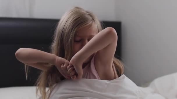 Linda menina criança acorda do sono na cama pela manhã . — Vídeo de Stock