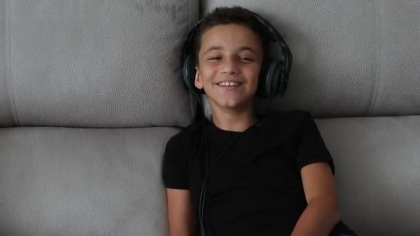 Kulaklıklı gülen genç çocuk bilgisayardan video izliyor. — Stok video