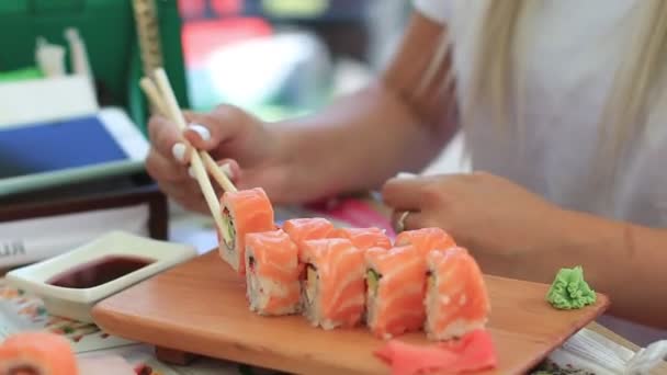 Ung kvinna i Café äta sushi med pinnar. Närbild — Stockvideo