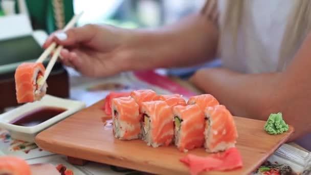 箸で女性の手のクローズアップショットは、醤油にセットされたスタイリッシュに置かれた寿司をダンクダンク — ストック動画