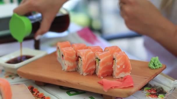 Kvinnan äter sushi. En kvinna häller sojasås — Stockvideo