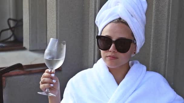Mladá žena pije šampaňské v hotelu na balkóně — Stock video