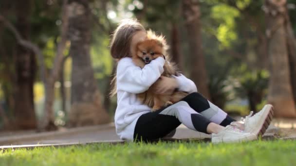 Hezká holčička dítě je objímání se svým roztomilým malým přítelem Pomeranian Spitz štěně — Stock video