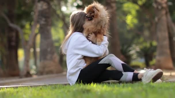 Krásná holčička dítě je objímání, chůze se svým roztomilým malým přítelem Pomeranian Spitz štěně — Stock video