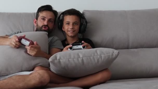 Baba ve küçük çocuk evde kanepede video oyunu oynuyor — Stok video