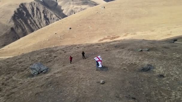 GUDAURI, GEORGIA - 17 november 2021: Achteraanzicht van gelukkige jongeman die poseert met de nationale vlag van Georgië die buiten staat — Stockvideo