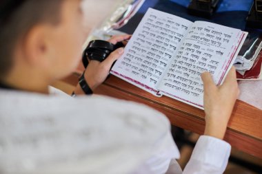 Genç bir adam bir Yahudi ayinine dua okurken İncil 'deki bir cümleyi işaret ediyor. Bar Mitzvah töreni