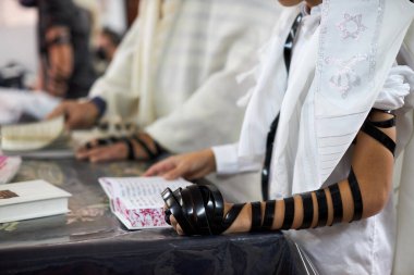 Yaklaş, genç adam Yahudi duası okuyor ve tefillin ve taliteyle el ele tutuşuyor.