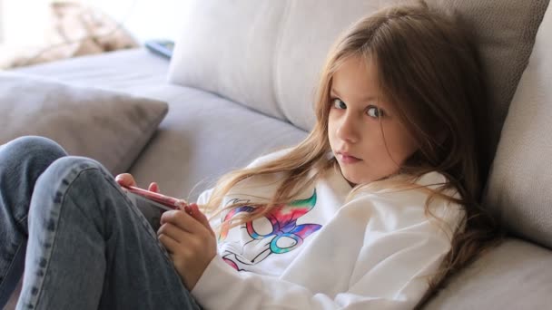Chica de la escuela en blusa blanca 9 años de edad jugando juego móvil en el teléfono — Vídeo de stock