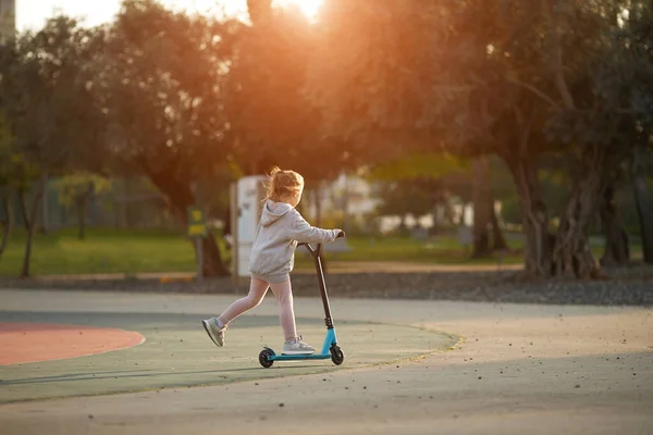 Niña hermosa monta un scooter en el parque — Foto de Stock