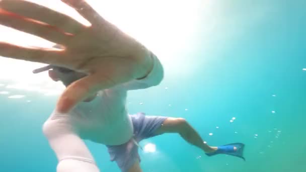 潜水和游泳。跳水一个戴着潜水面具的男人带着无数五彩斑斓的鱼在海底探索珊瑚礁 — 图库视频影像