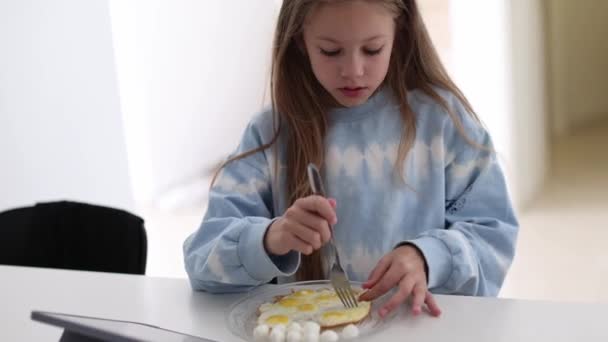 Маленькая Девочка Завтракает Дома Кухне Смотрит Свой Планшет Счастливый Ребенок — стоковое видео
