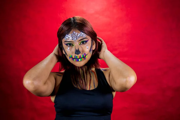 Young woman with makeup for halloween party, costume party, red background.
