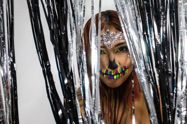 Cadılar bayramı partisi için makyajlı, gümüş ve siyah şeritlerin arkasına saklanan genç bayanın yakın çekimleri..