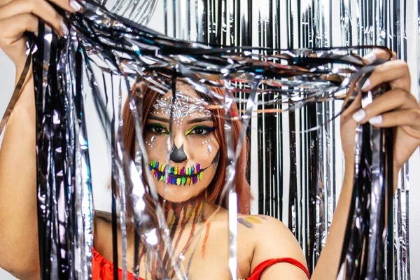 Cadılar bayramı partisi için makyajlı, gümüş ve siyah şeritlerin arkasına saklanan genç bayanın yakın çekimleri..