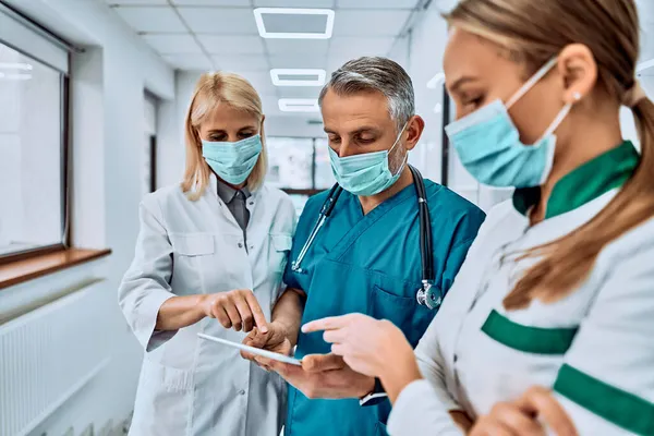 Três Médicos Mascarados Com Tablet Corredor Hospital Verificar Uma Coisa — Fotografia de Stock
